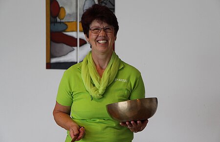 Frau Margarete Günter mit einer Klangschale in der Hand.