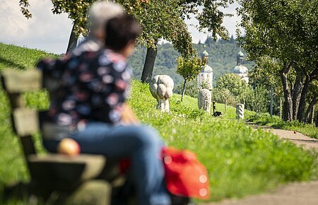 Zwei Wanderer auf einer Bank am Andachtsweg zur Wallfahrtsbasilika Maria Brünnlein.