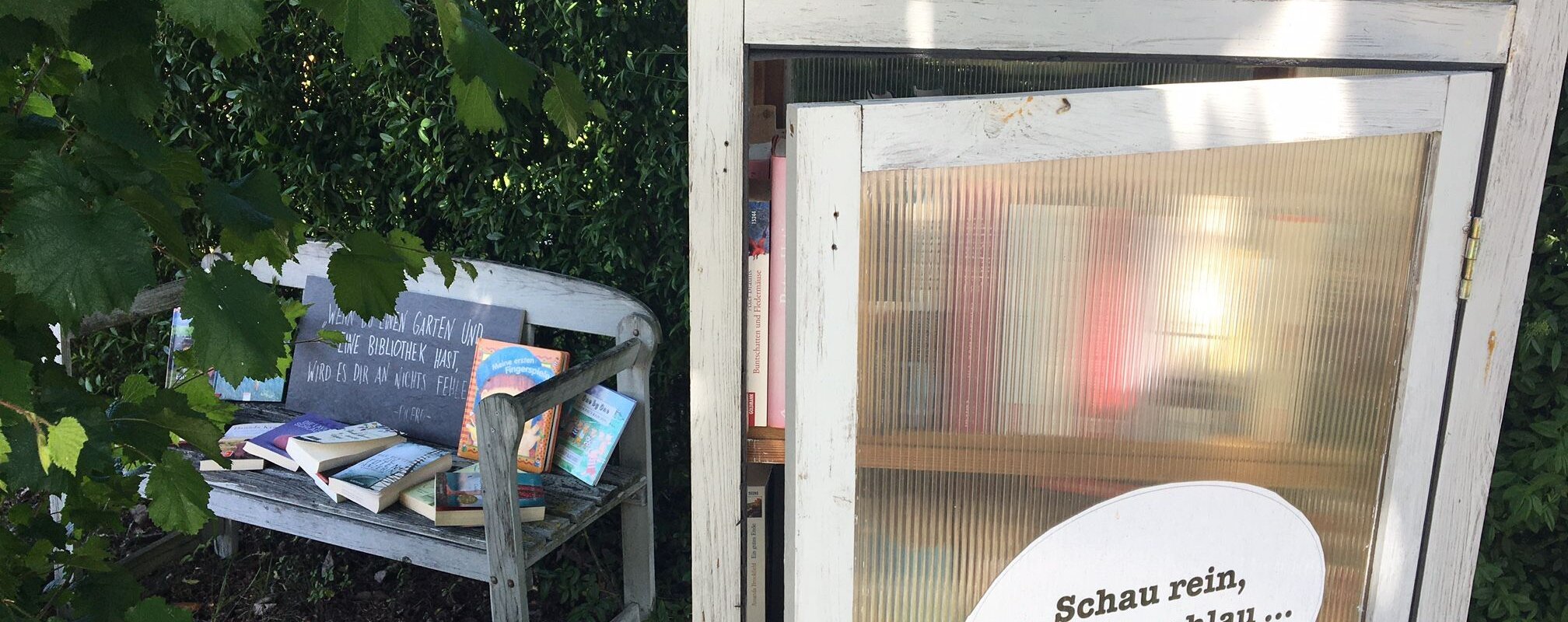 Blick auf den öffentlich zugänglichen Bücherschrank in der Bürgermeister-Rößner-Straße 1 in Buchdorf mit daneben stehender Sitzgelegenheit.