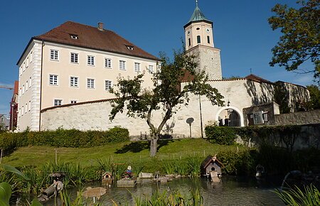 Blick auf das ehemalige Schloss Gosheim mit davor liegendem Weiher. Rechts neben dem Schloss sieht man den Turm der Pfarrkirche Mariä Geburt.
