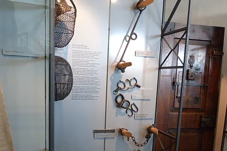 Ausgestelltes Folterwerkzeug in einer Vitrine