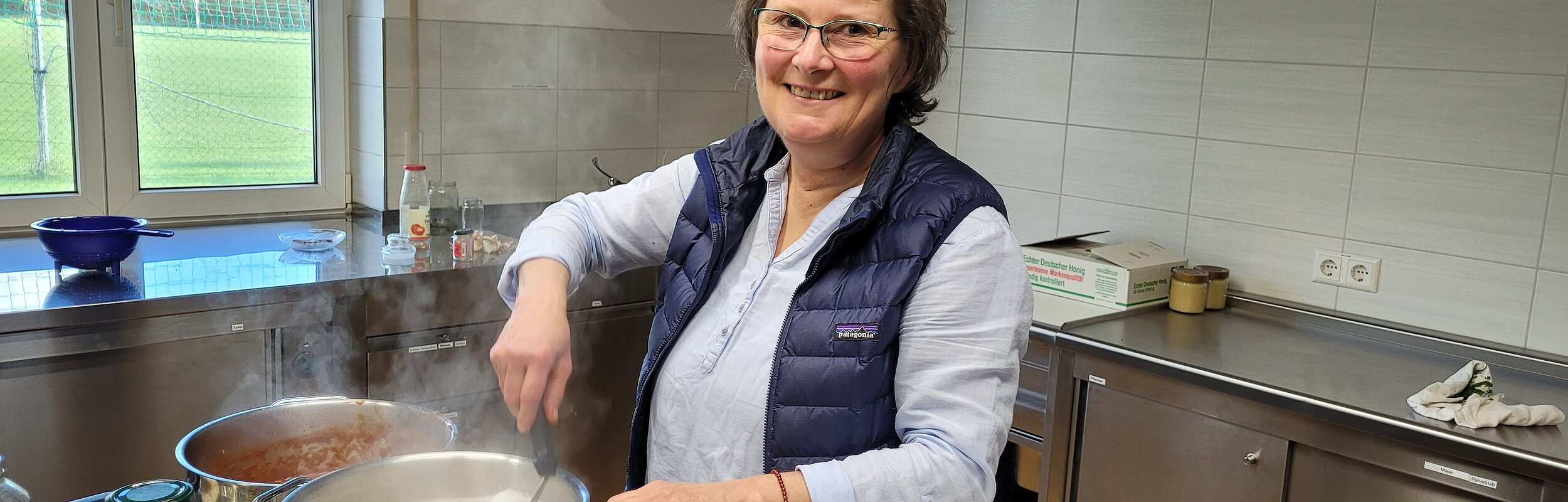 Eine Frau steht am Herd und kocht etwas in einem Topf.