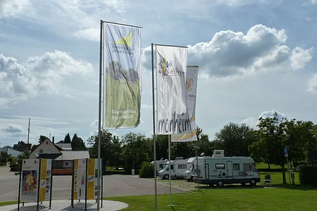 Die Geopark Infostelle mit Flaggen und im Hintergrund die Wohnmobile auf dem Wohnmobilstellplatz in Monheim