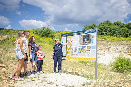 Eine Geopark Ries Führerin zeigt einer kleinen Gruppe Personen eine Informationstafel.