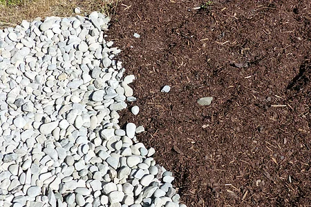 Kneipp-Gesundheitsanlage Monheim - Barfußpfad Weiße Kieselsteine grenzen an eine Fläche mit braunem Mulch.