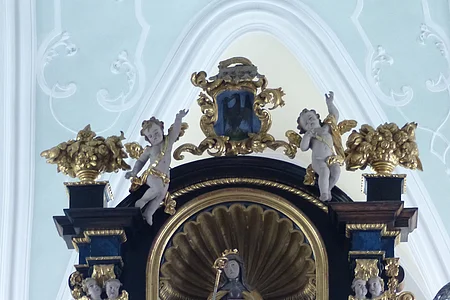 Barockes Altarretabel mit goldener Skulptur und Putten, verziert mit floralen Elementen und Engelsköpfen.