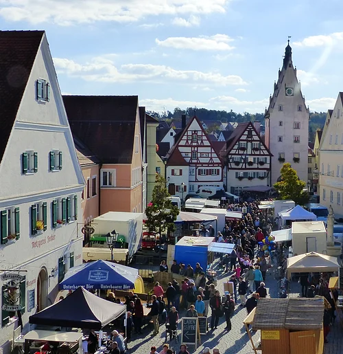 Schärtlesmarkt in Monheim Menschenmenge auf dem belebten Monheimer Marktplatz mit historischen Gebäuden und vielen Verkaufsständen bei sonnigem Wetter.