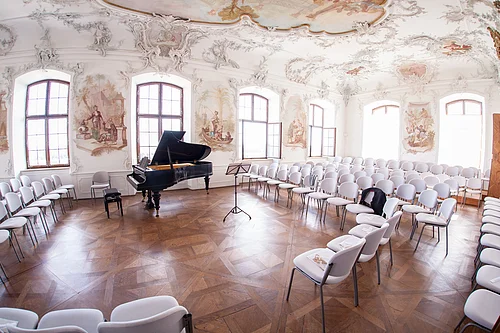 Konzertsaal Ein Blick in den Rokokofestsaal von Schloss Leitheim, vorbereitet für ein Konzert mit Flügel und Bestuhlung.