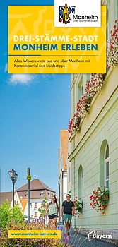 Titelseite des Flyers "Drei-Stämme-Stadt Monheim erleben" zum Stadt Monheim in der Monheimer Alb. Der Titel ist in weiß-blauen Großbuchstaben auf gelben Hintergrund geschrieben. Auf dem Foto zwei Personen, die an einem grünem Haus mit Blumenkästen entlanggehen in einer Straße in Monheim, Bayern. Oben rechts im Eck das Log der Stadt Monheim.