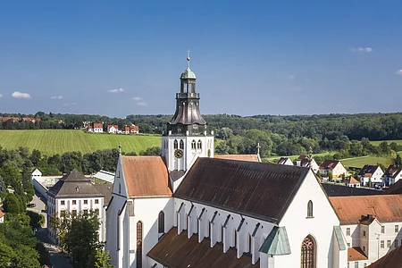 Luftaufnahme einer großen weißen Kirche mit rotem Dach in einer ländlichen Stadt bei klarem Himmel.