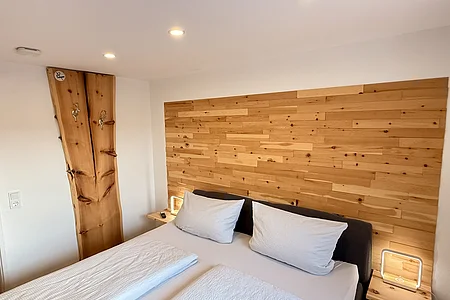 Hotelzimmer mit Doppelbett, Holzwand und zwei Nachttischen mit Lampen und Fernbedienung